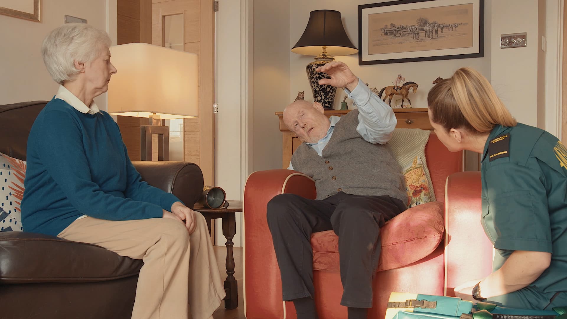 An old lady and a female paramedic looking at a suspected stroke male patient